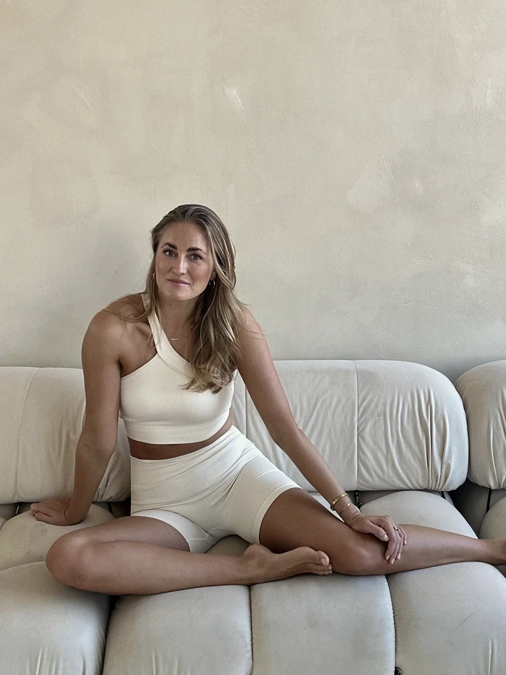 Matilde seated on a light sofa in white clothing